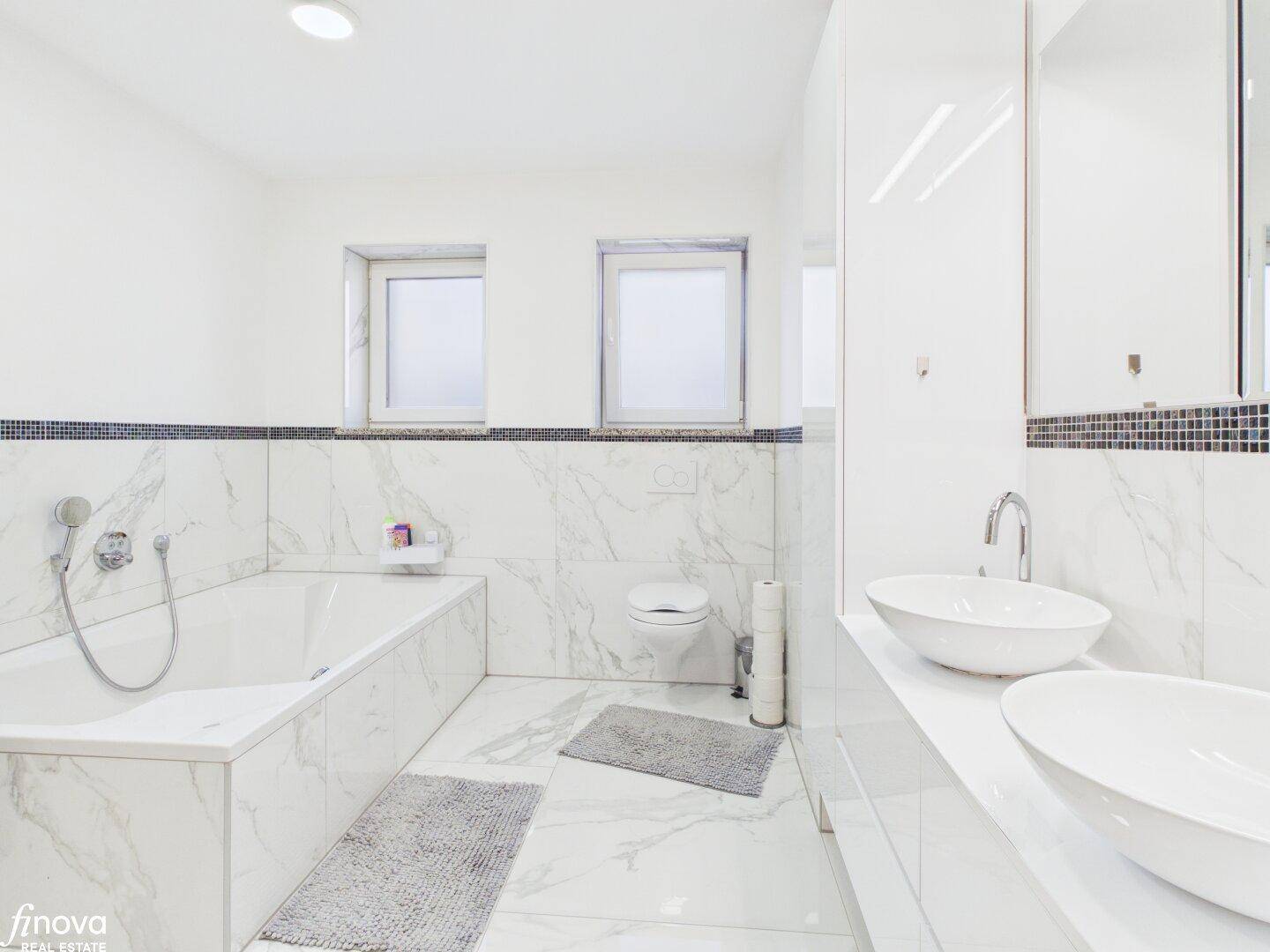 Geräumiges Badezimmer mit Badewanne, Doppelwaschbecken und Marmorfliesen.