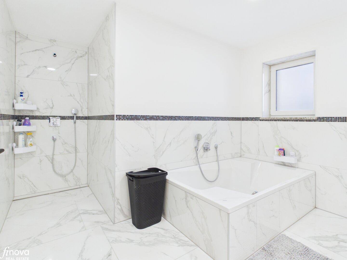 Modernes Badezimmer mit Badewanne, Dusche und Marmorfliesen.