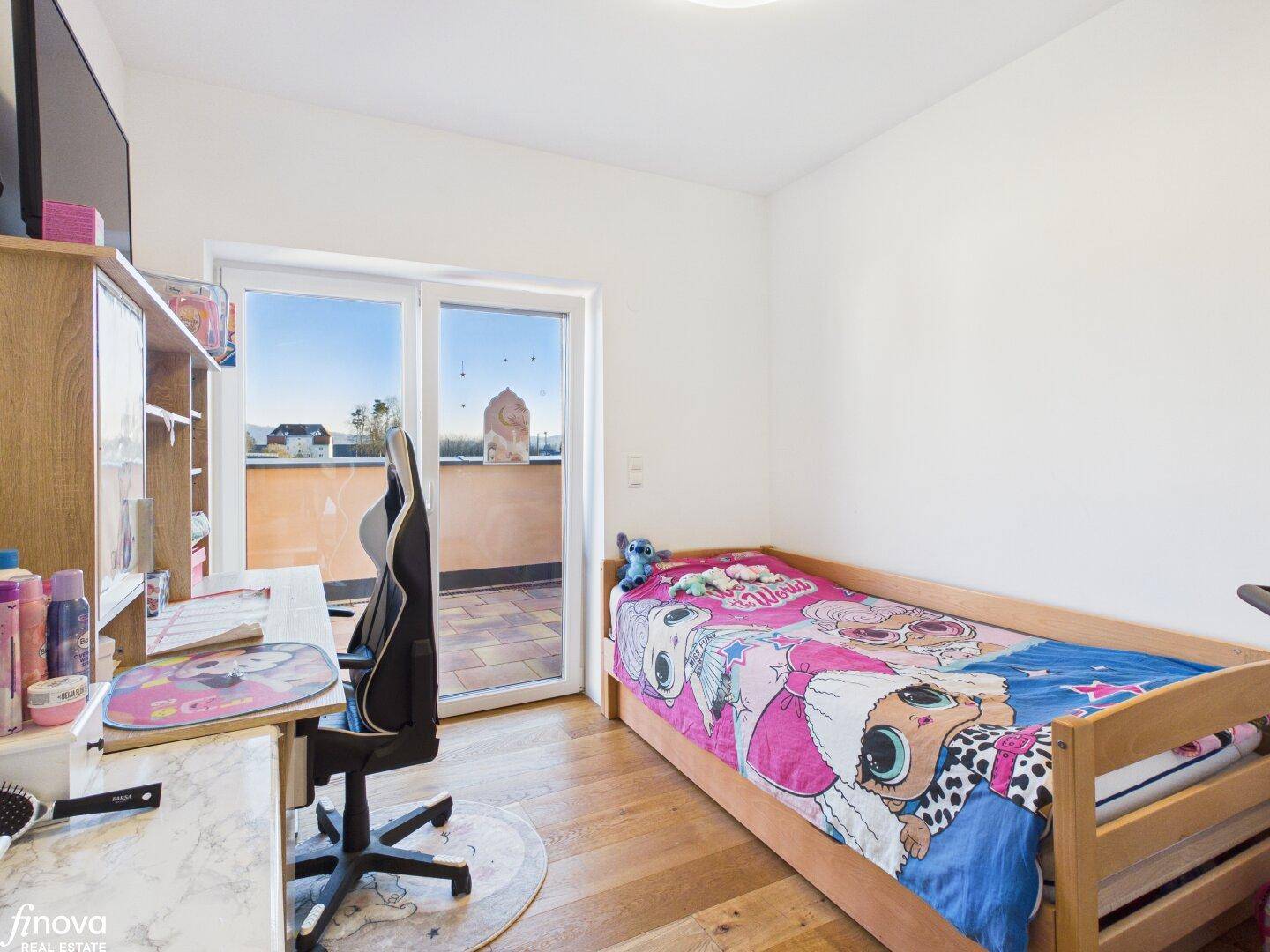 Kinderzimmer mit Holzboden, Schreibtisch und Zugang zur Terrasse.