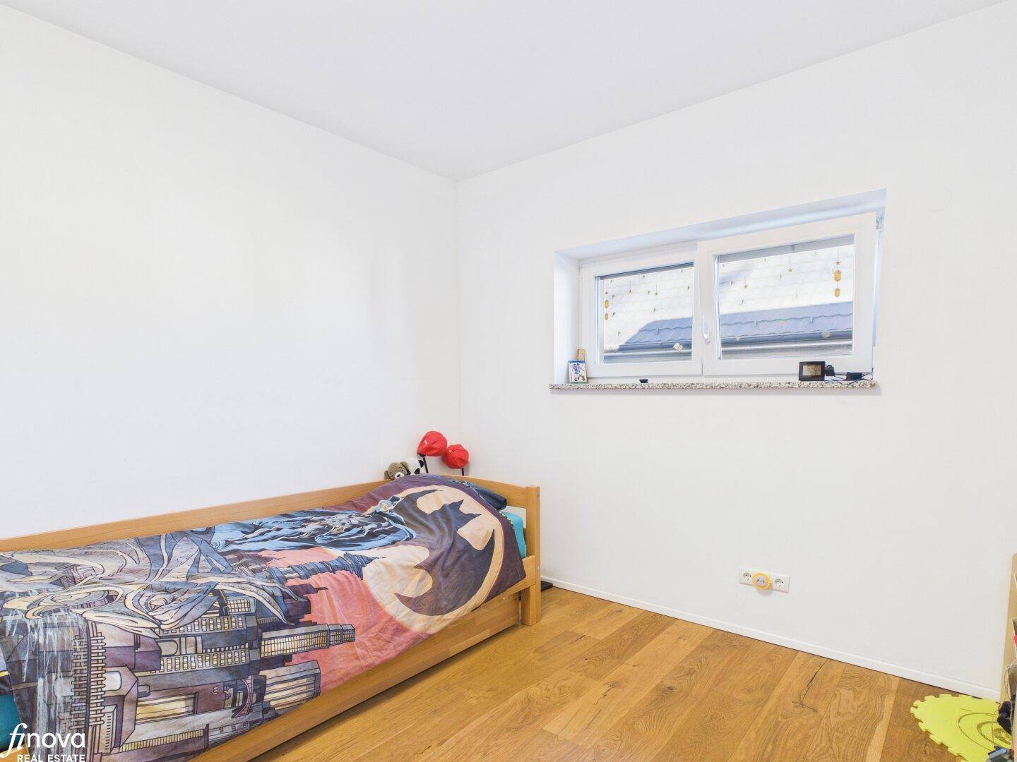 Kinderzimmer mit Holzboden und Fenster, ideal für junge Bewohner.