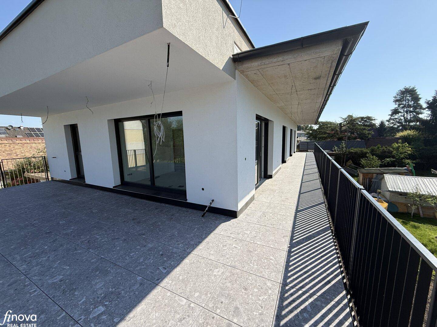 Geräumige Terrasse mit Fliesenboden und moderner Fassade, bietet viel Platz im Freien.