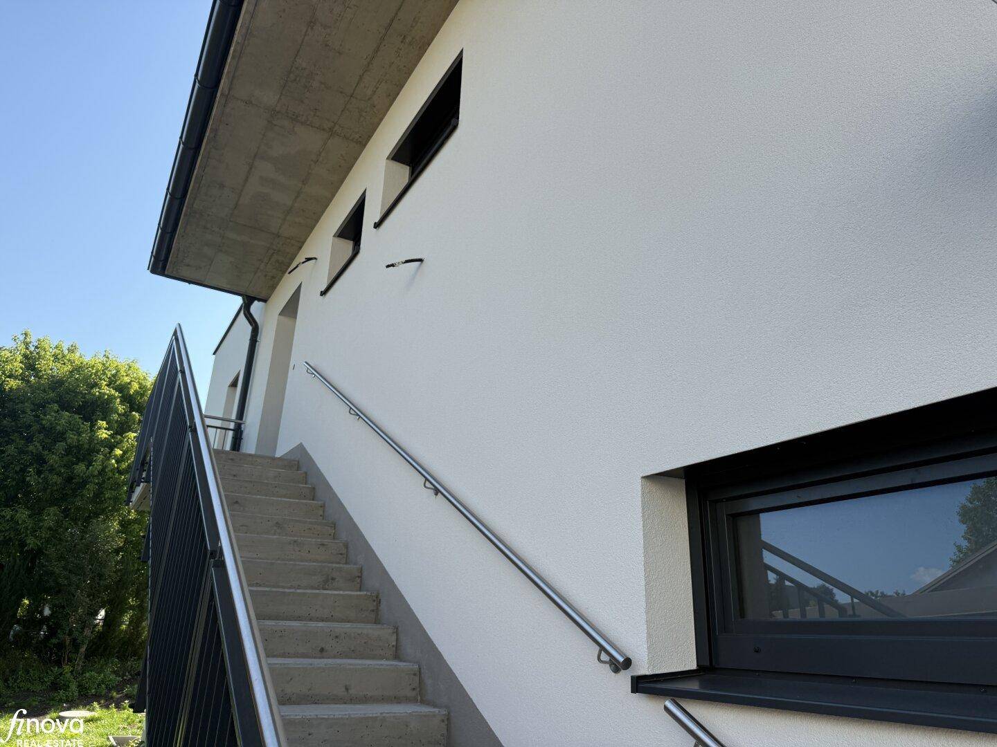 Außentreppe mit Metallgeländer führt zum oberen Stockwerk des modernen Neubaus.