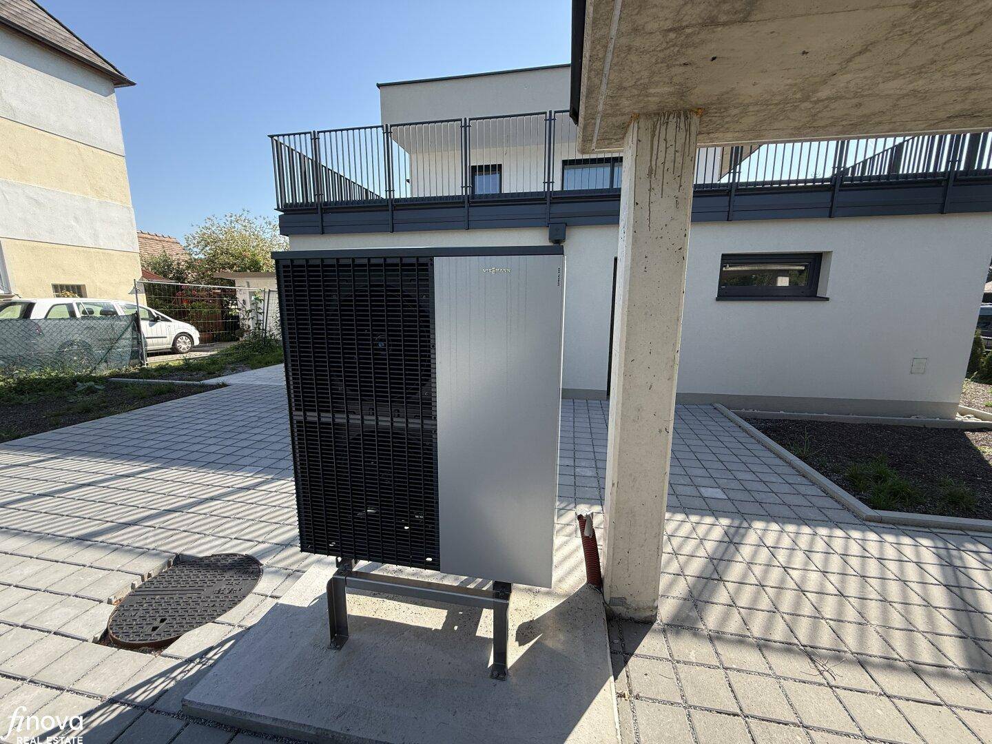 Außenansicht der modernen Wärmepumpe, die neben dem Gebäude auf einem gepflasterten Bereich installiert ist.