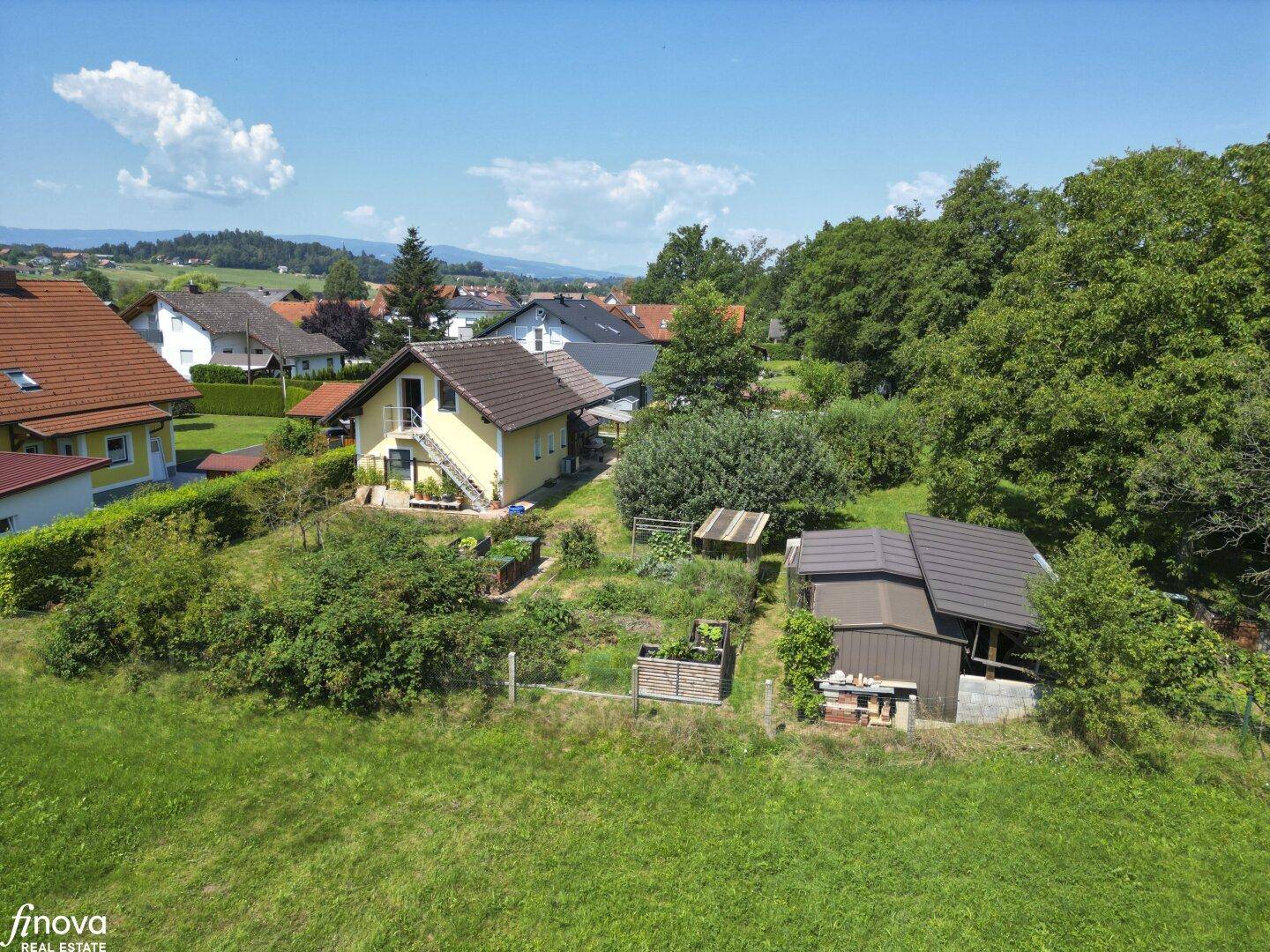 Weitläufige Luftaufnahme des Hauses mit großem Garten, Hochbeeten und einem Nebengebäude.