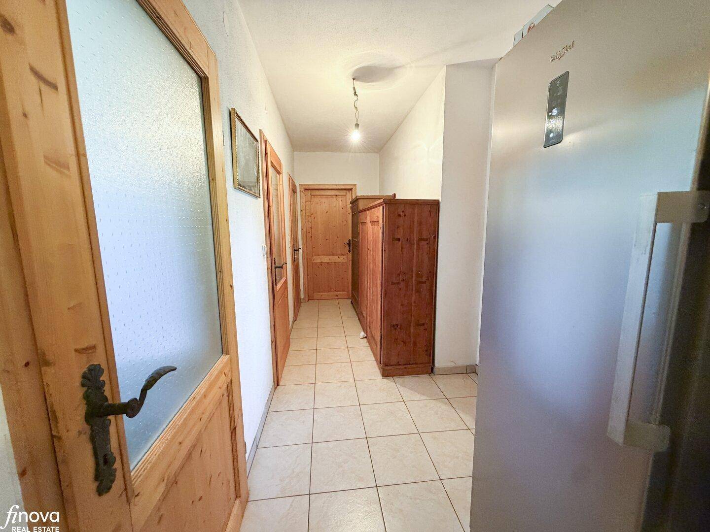 Heller Flur mit Fliesenboden, Holzmöbeln und Zugang zu weiteren Räumen.