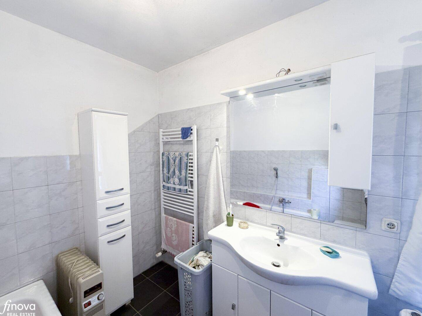 Modernisiertes Badezimmer mit Waschtisch, Spiegelschrank und beheiztem Handtuchhalter.