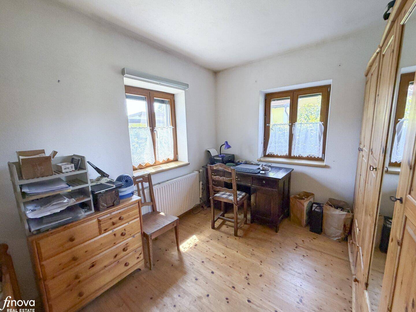 Schlafzimmer mit Holzboden, Schreibtisch und traditionellen Holzmöbeln.