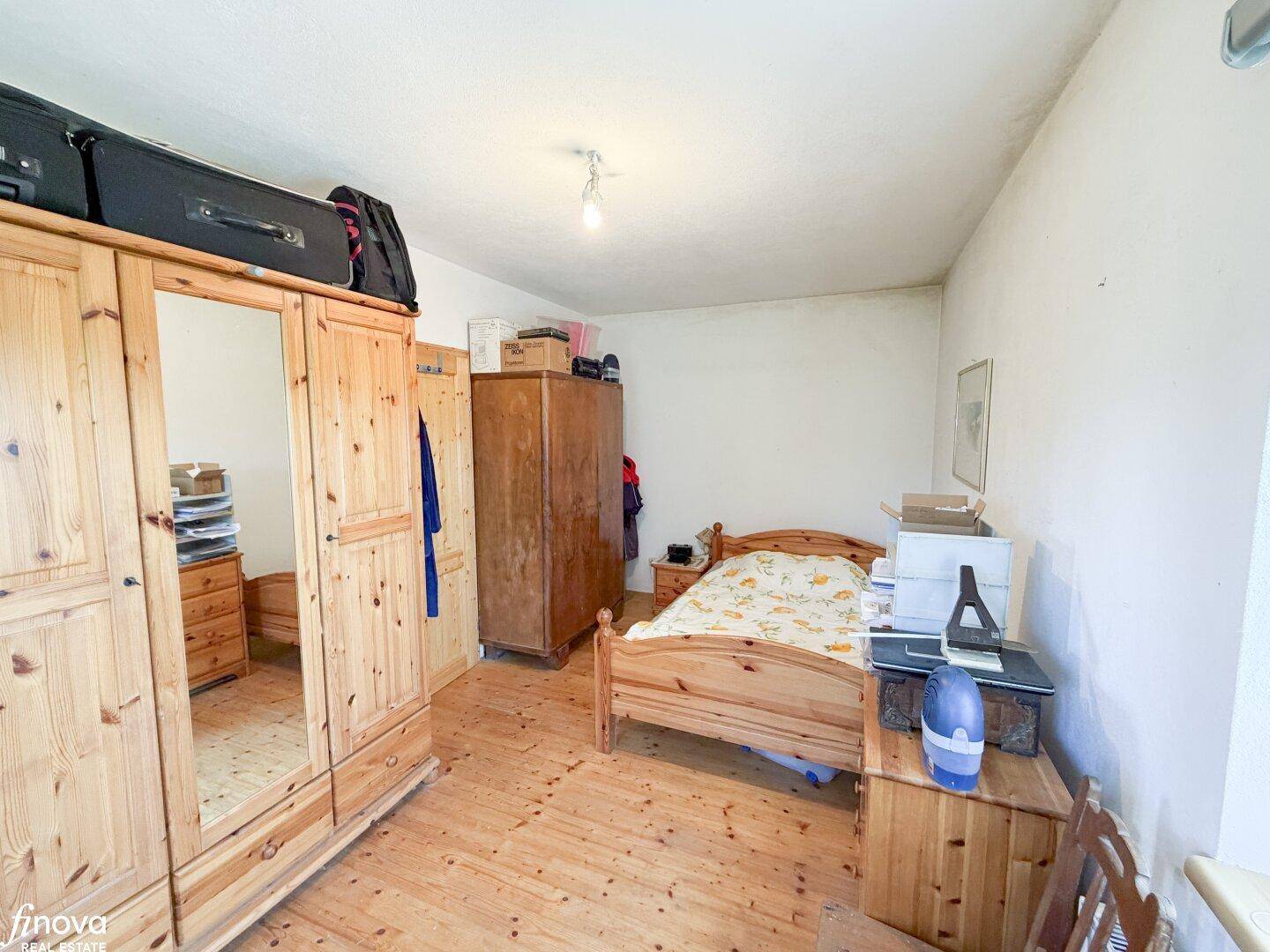 Schlafzimmer mit Holzboden, Holzmöbeln und einfacher, funktionaler Einrichtung.