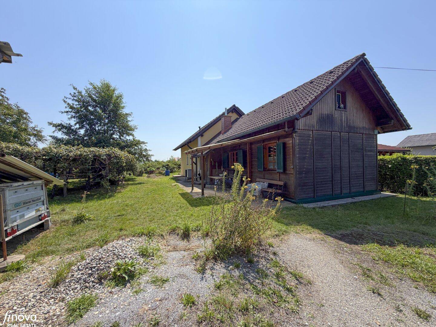 Seitenansicht des Hauses mit Garten, Schotterweg und viel Grünfläche.