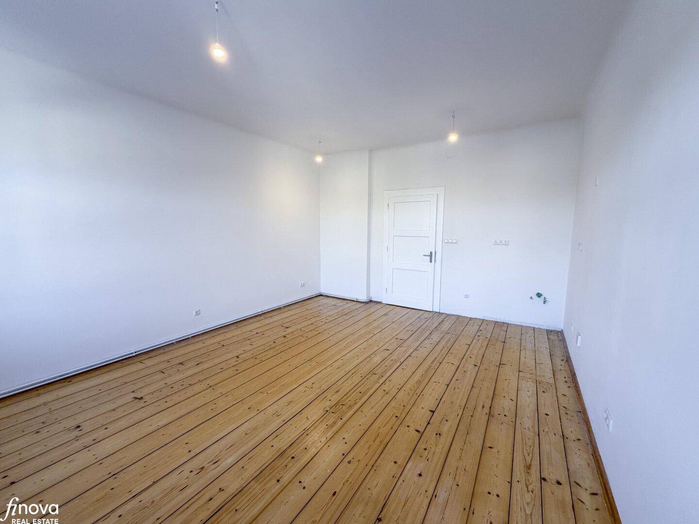 Geräumiger Raum mit Holzdielenboden und weiß gestrichenen Wänden, ideal für Wohn- oder Schlafbereich.