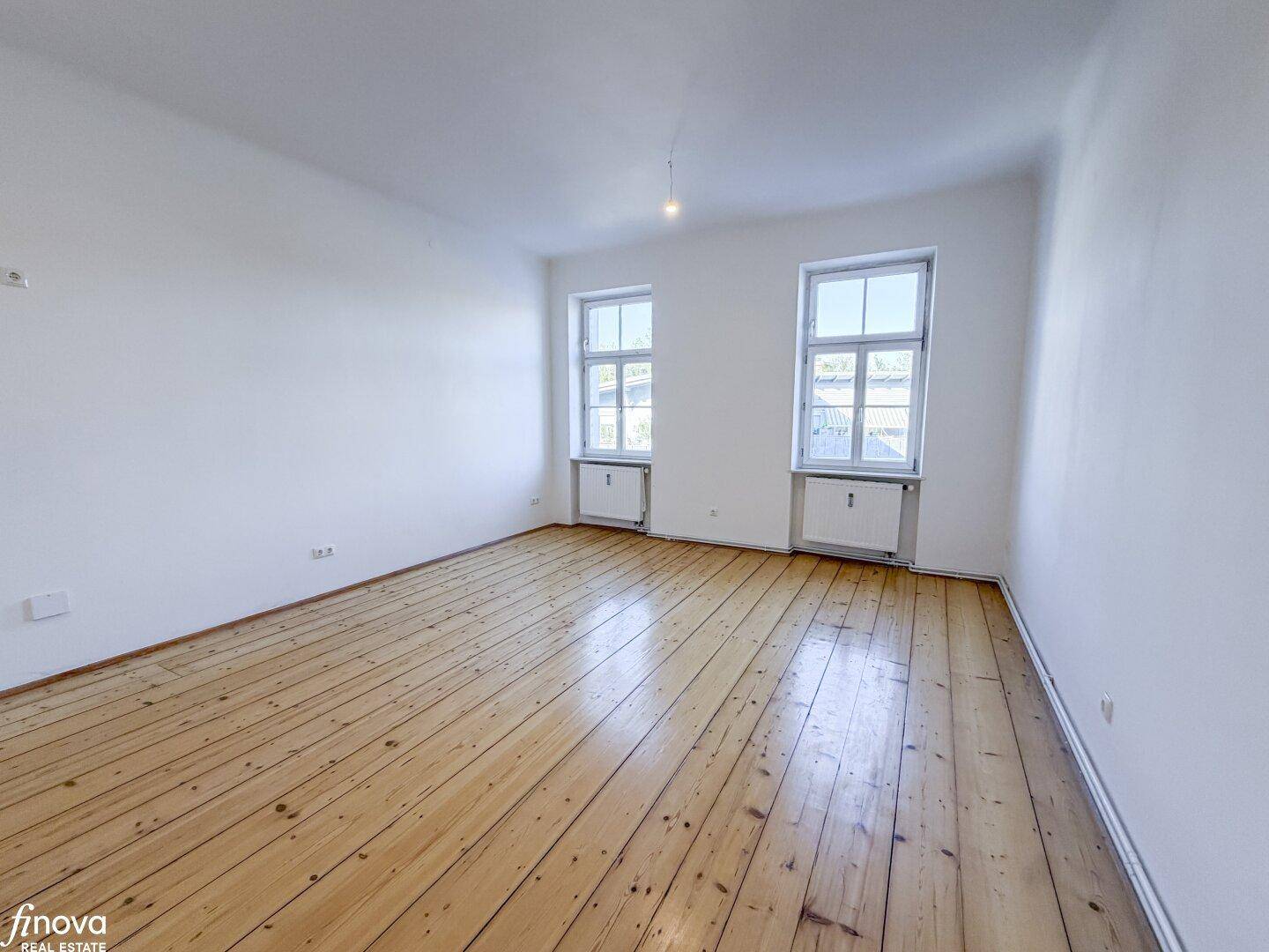 Weitläufiges Zimmer mit klassischem Holzdielenboden und hellen Wänden, bietet eine angenehme Atmosphäre.