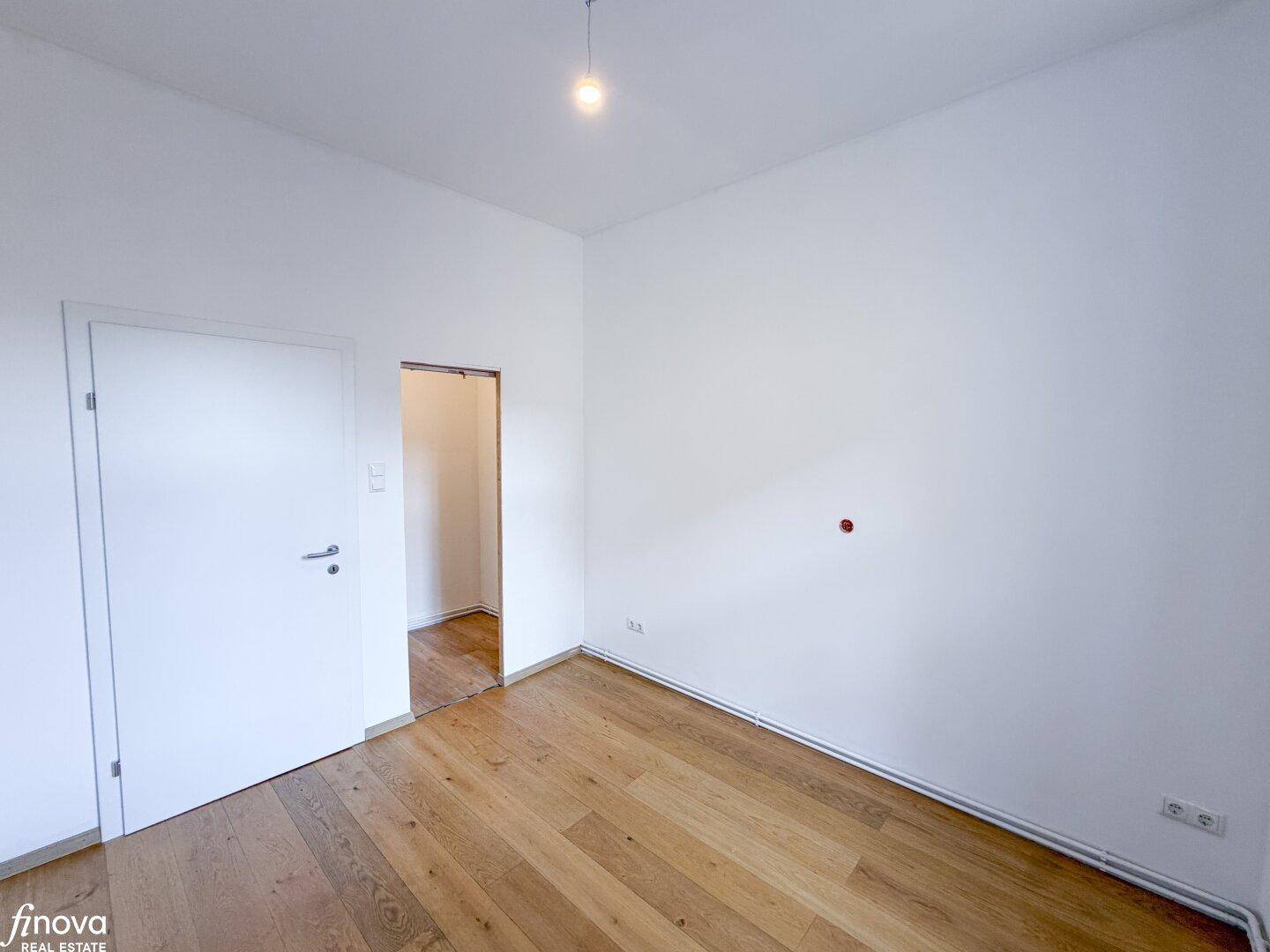 Geräumiges Zimmer mit hellem Holzboden und weiß gestrichenen Wänden, ideal als Schlafzimmer.