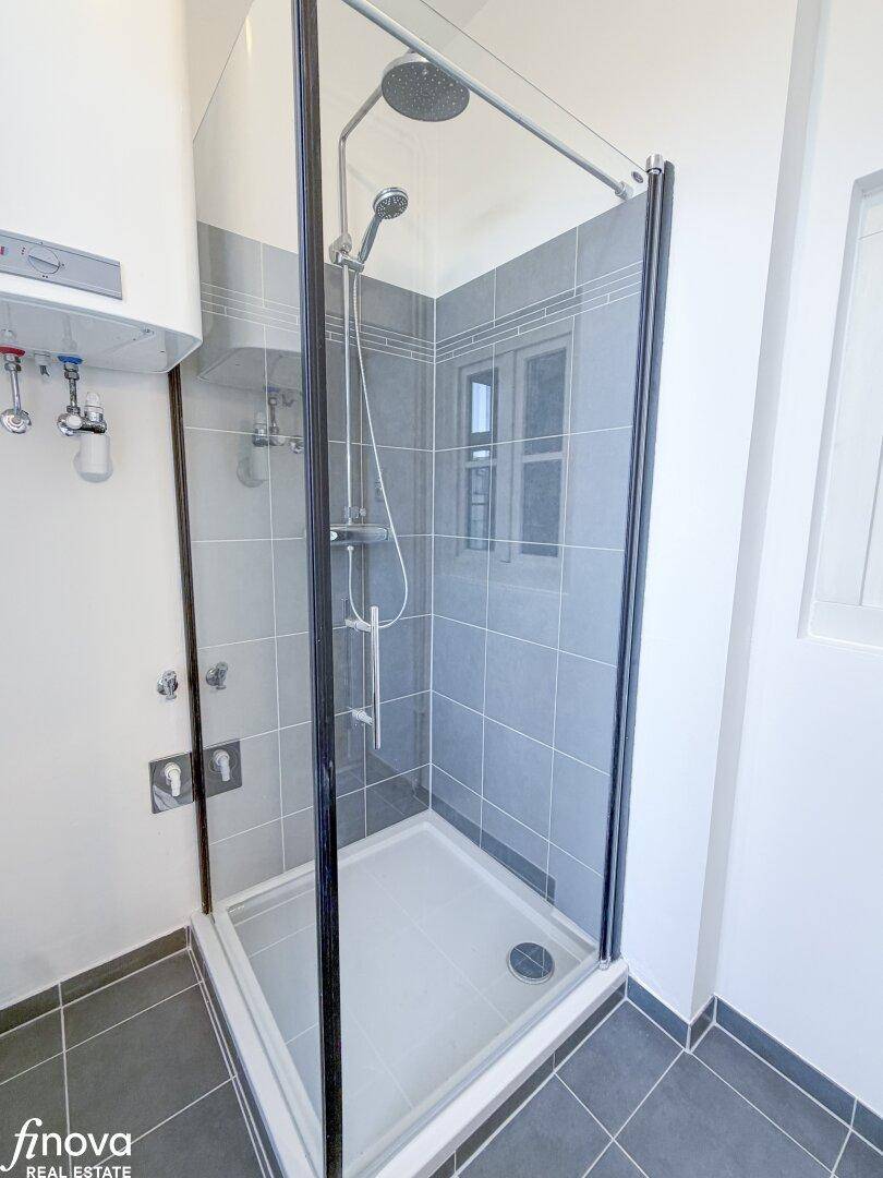 Moderne Duschkabine mit Regenduschkopf und grauen Wandfliesen, bietet Komfort und Stil.