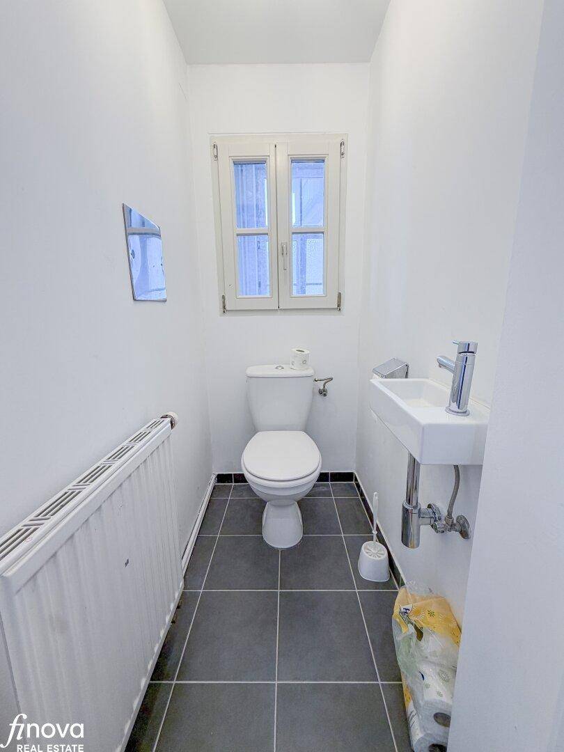 Kleines Gäste-WC mit Fenster, Toilette und Handwaschbecken, praktisch und hell.