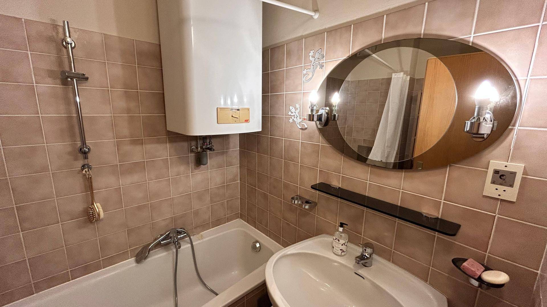 Badezimmer mit Badewanne, Waschbecken und Fliesen in warmem Braunton.