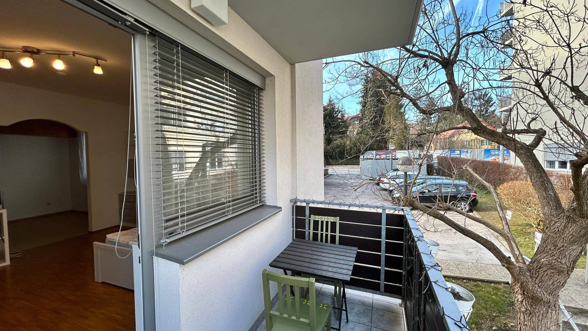 Kleiner Balkon mit Sitzgelegenheiten und Blick auf die Umgebung und Bäume.