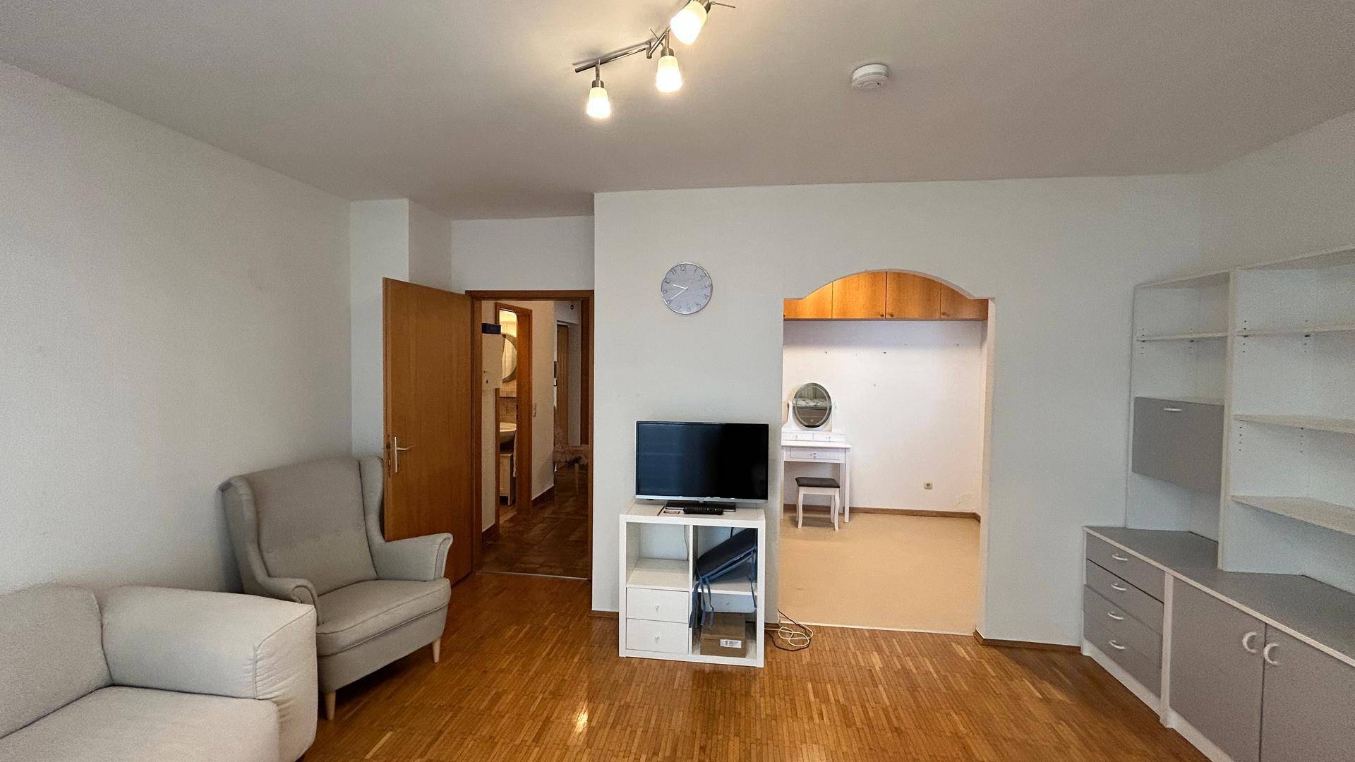 Wohnzimmer mit Parkettboden und Blick auf den angrenzenden Raum mit Schminktisch.