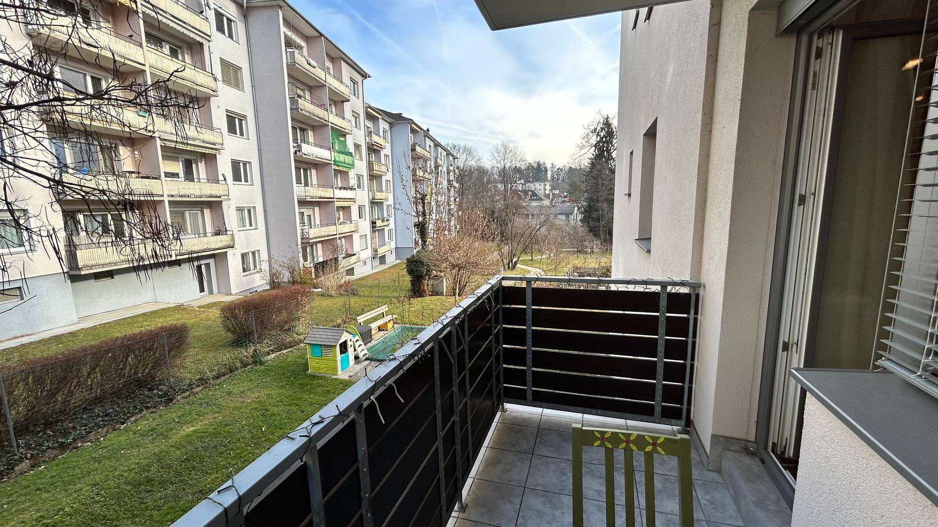Balkon mit Blick auf die grüne Gartenanlage und die umliegenden Wohngebäude.