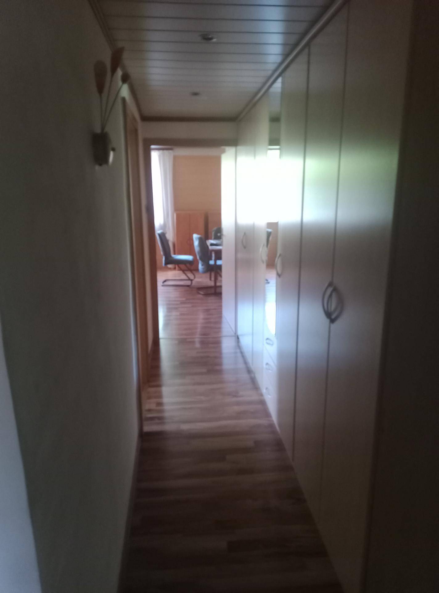 Langer Flur mit Laminatboden und integrierten Schränken, der zu einem Essbereich führt.