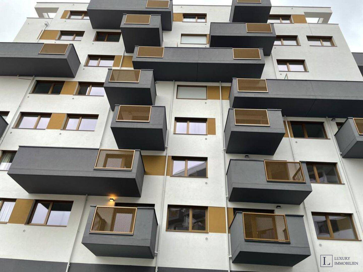 Moderne Wohnhausfassade mit vielen gestaffelten Balkonen und zeitgenössischer Architektur.