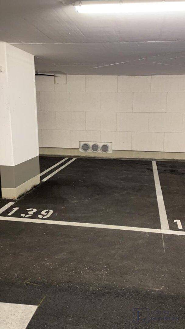 Leerer Parkplatz in einer Tiefgarage mit Markierungen auf dem dunklen Boden.