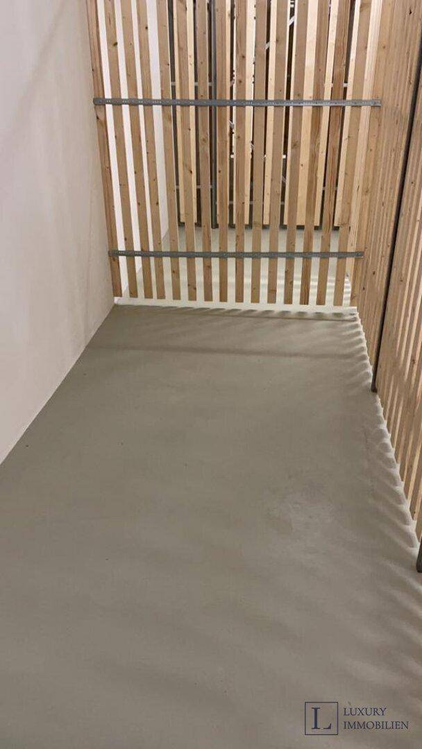 Leerer Lagerbereich mit Betonboden und Holzabtrennungen im Untergeschoss des Gebäudes.