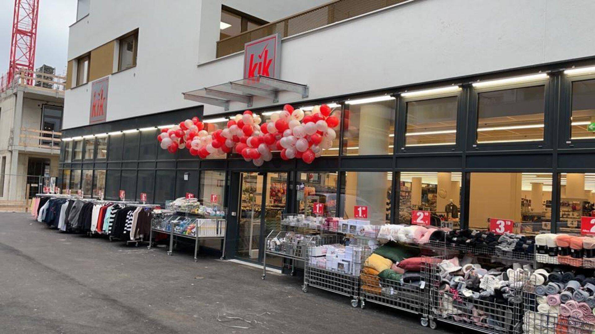 Eingangsbereich eines KiK-Geschäfts mit Luftballondekoration und Auslagen im Erdgeschoss.
