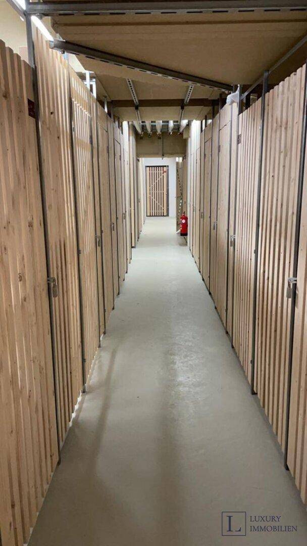 Langer Gang mit vielen individuellen Lagerabteilen im Kellerbereich des Gebäudes.