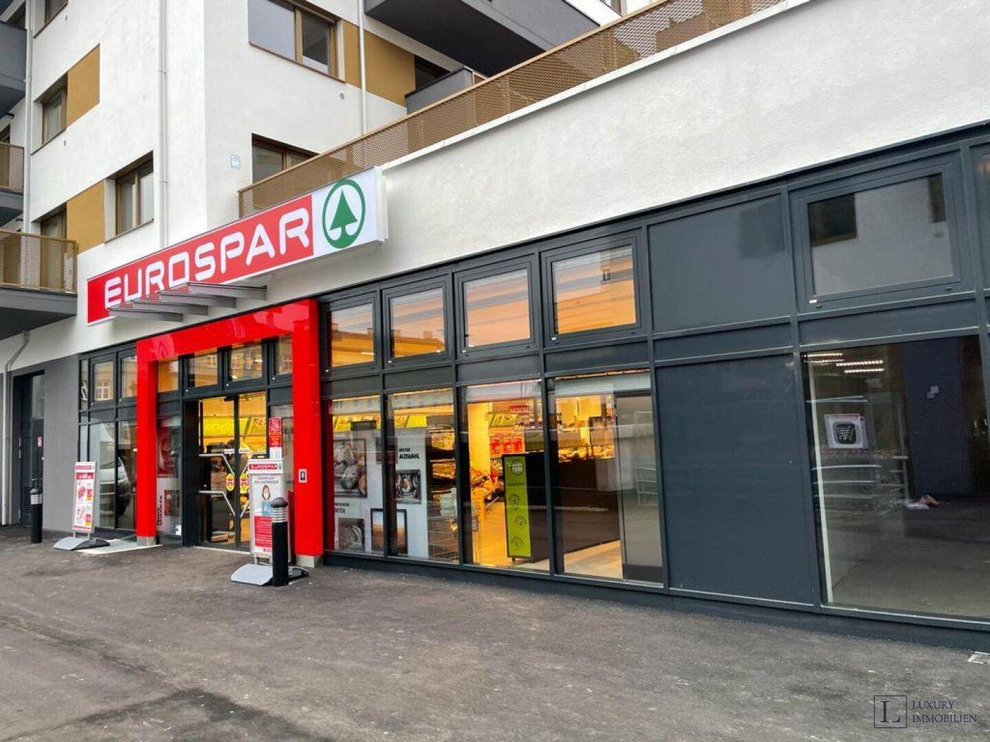 Eingangsbereich eines Eurospar-Supermarktes im Erdgeschoss eines modernen Gebäudes.