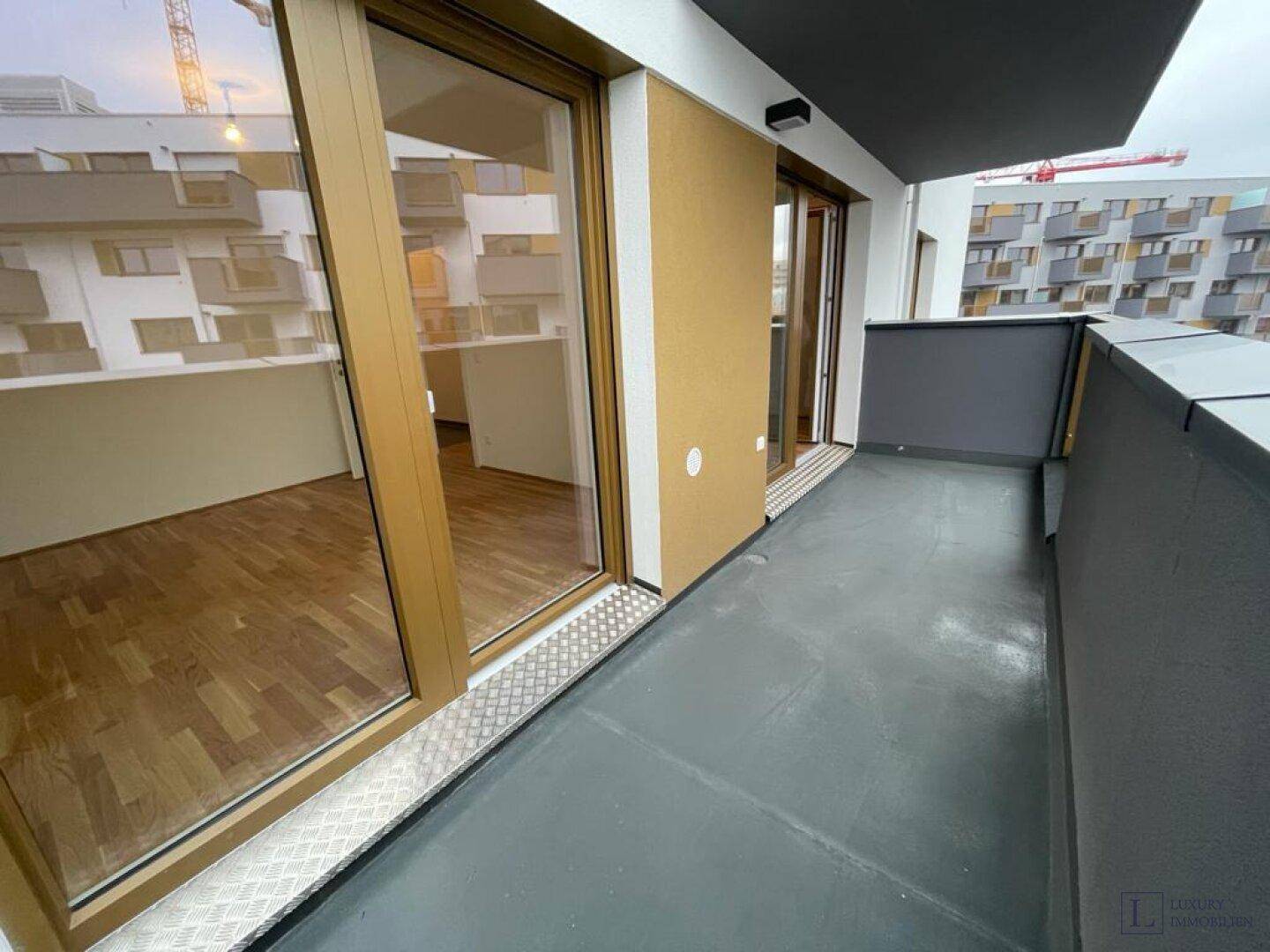 Breiter Balkon mit Zugang zum Innenraum und Blick auf die benachbarten Gebäude.