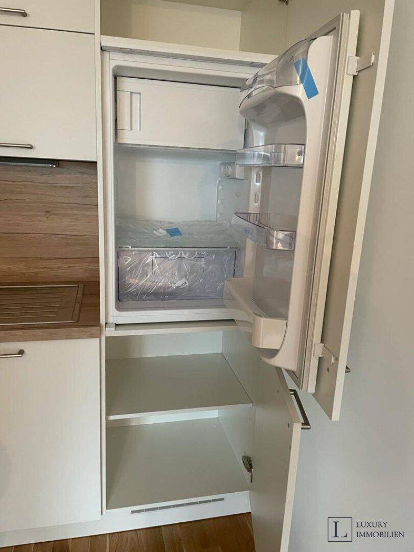 Offener Kühlschrank mit integriertem Gefrierfach als Teil einer neuen Küchenzeile.
