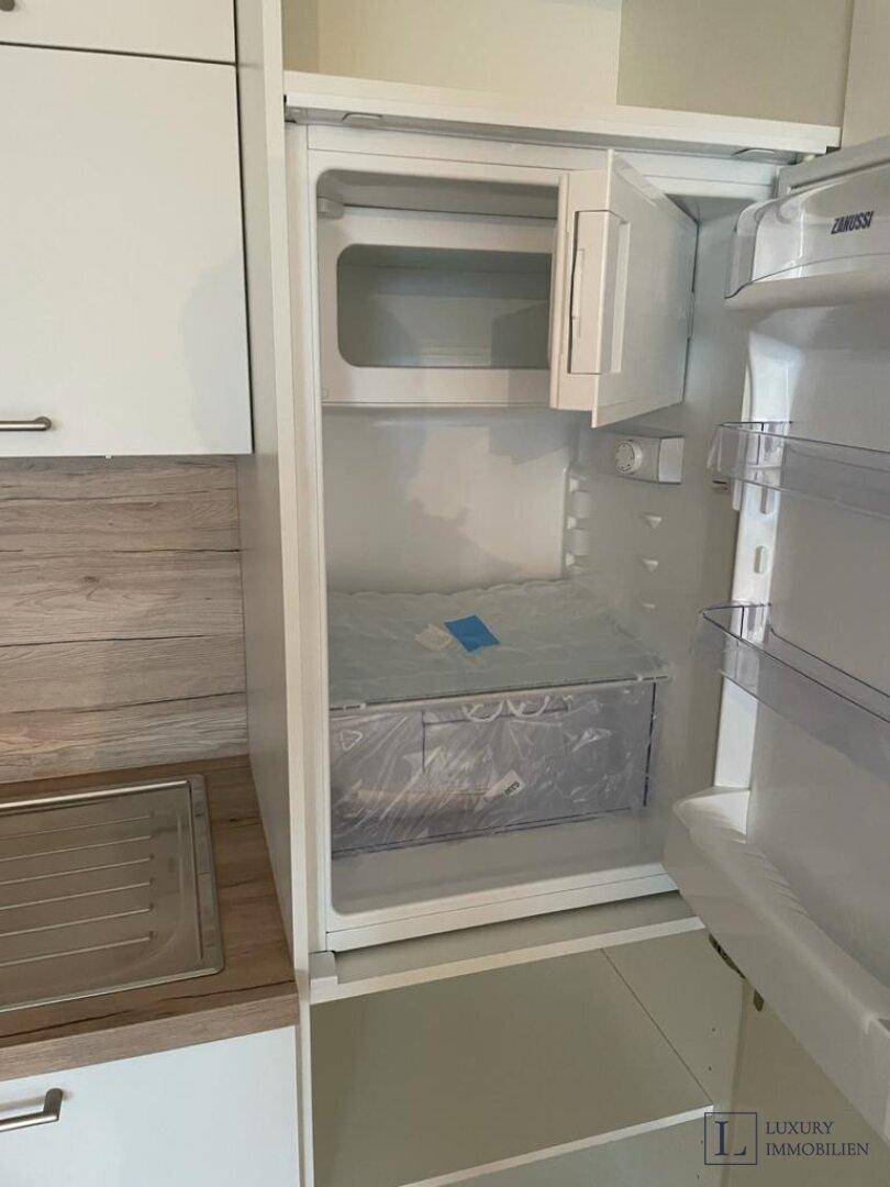 Integrierter Kühlschrank mit Gefrierfach in einer modernen, unbenutzten Einbauküche.