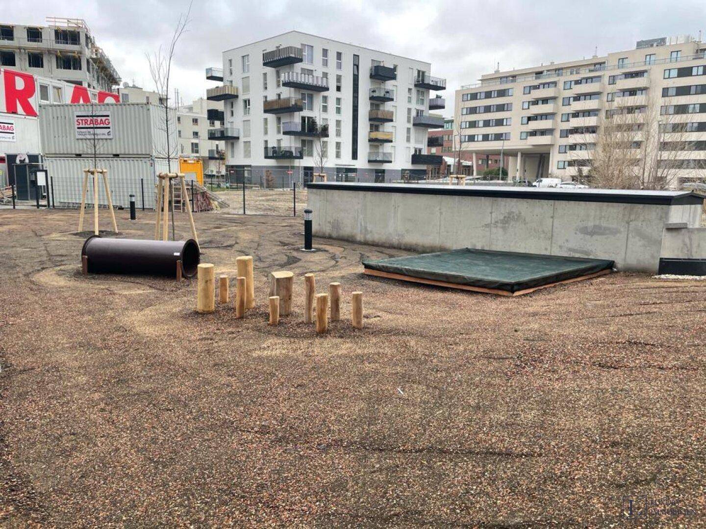 Außenbereich mit Spielgeräten und Sitzgelegenheiten für Kinder in einer Wohnanlage.