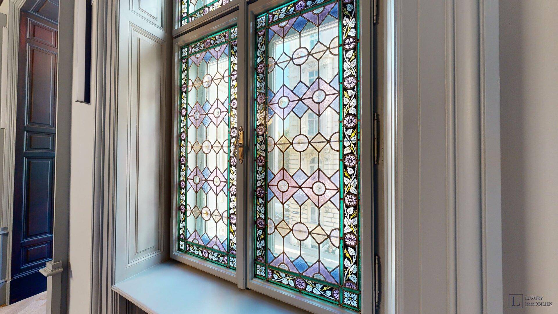 Detailansicht eines kunstvollen Buntglasfensters mit geometrischen Mustern.