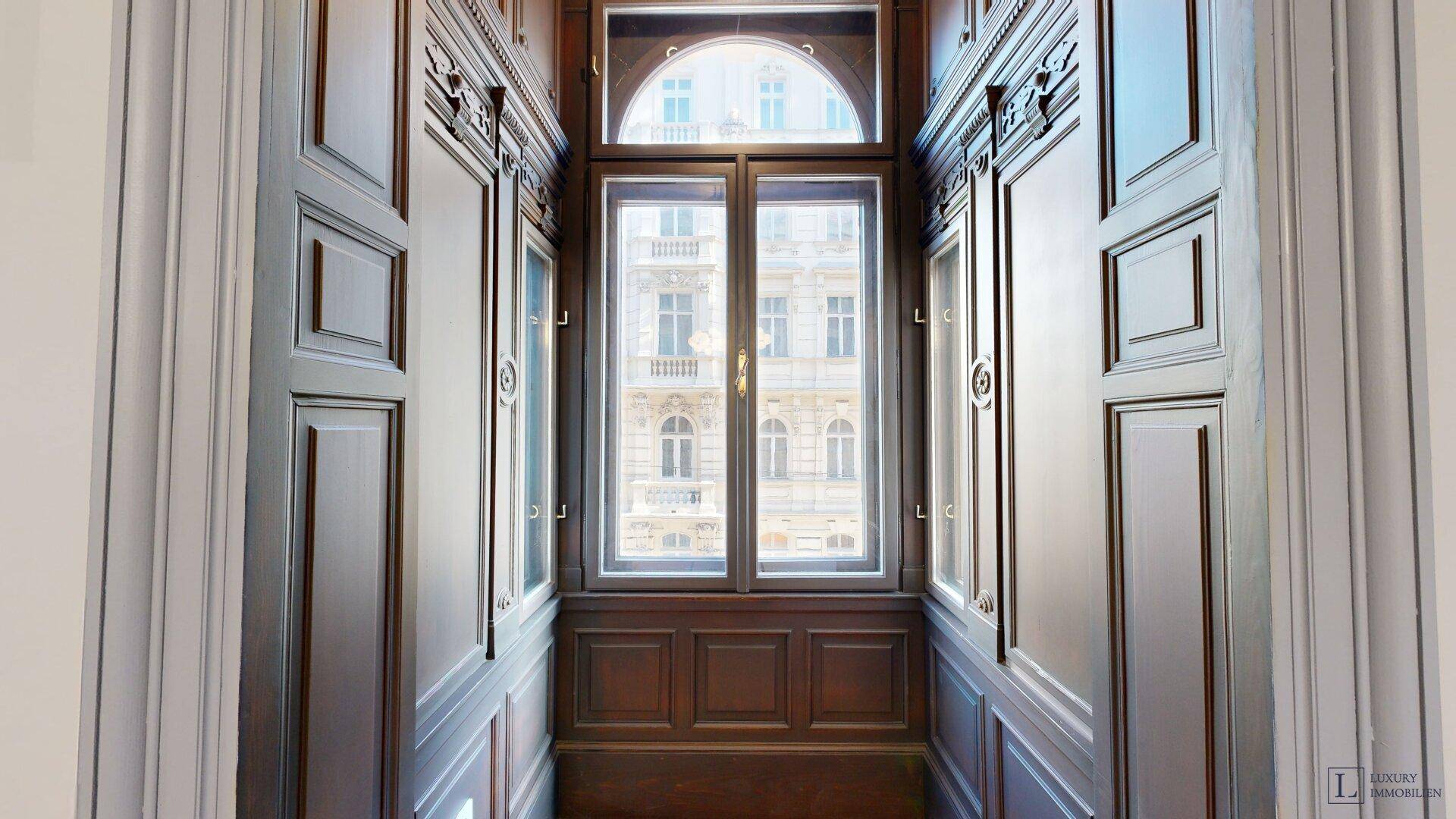 Historischer Durchgangsbereich mit Holztäfelung und einem großen Fenster mit Rundbogen.