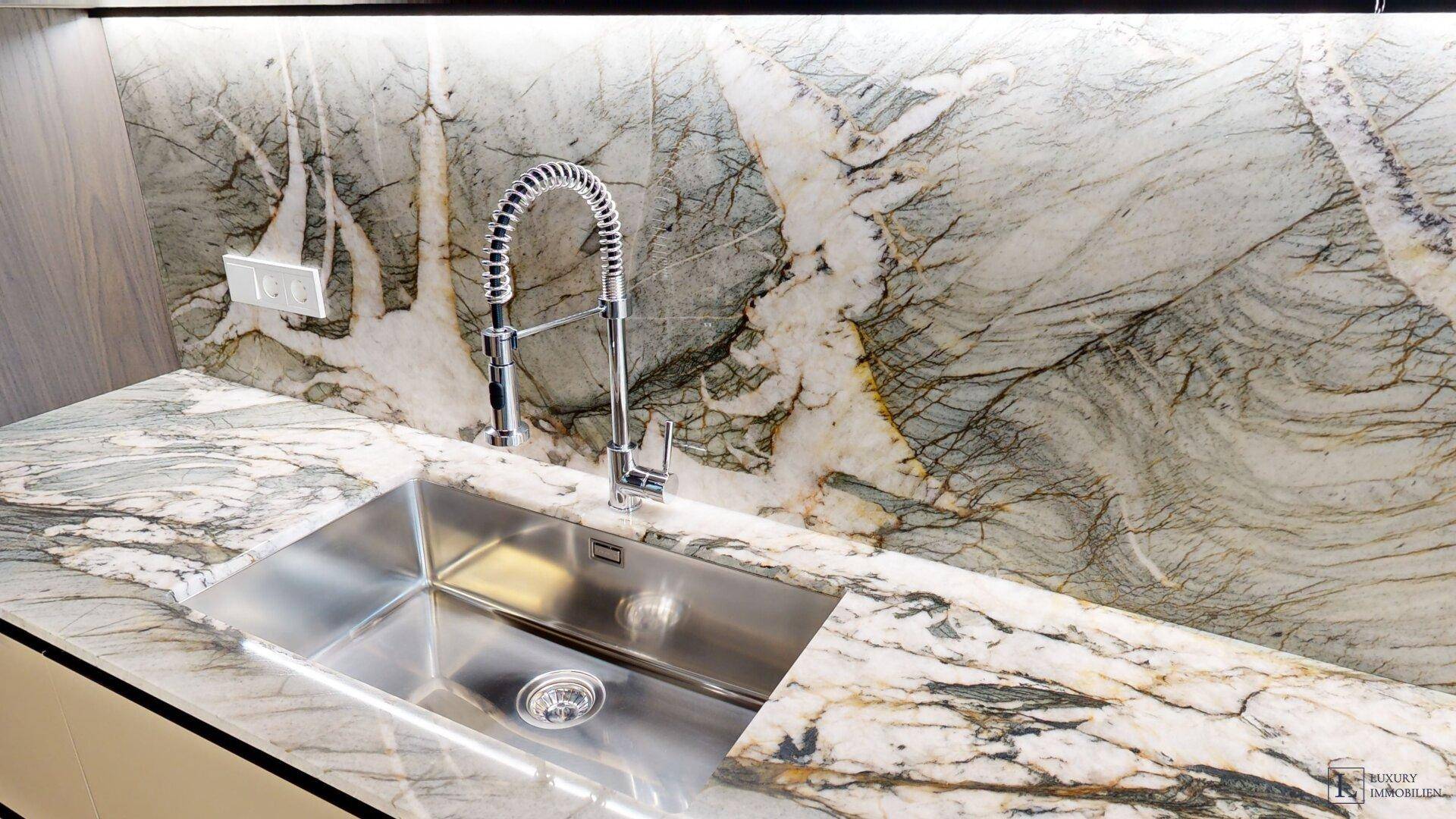 Detailansicht der Küchenspüle mit modernem Wasserhahn und gemusterter Marmorarbeitsplatte.