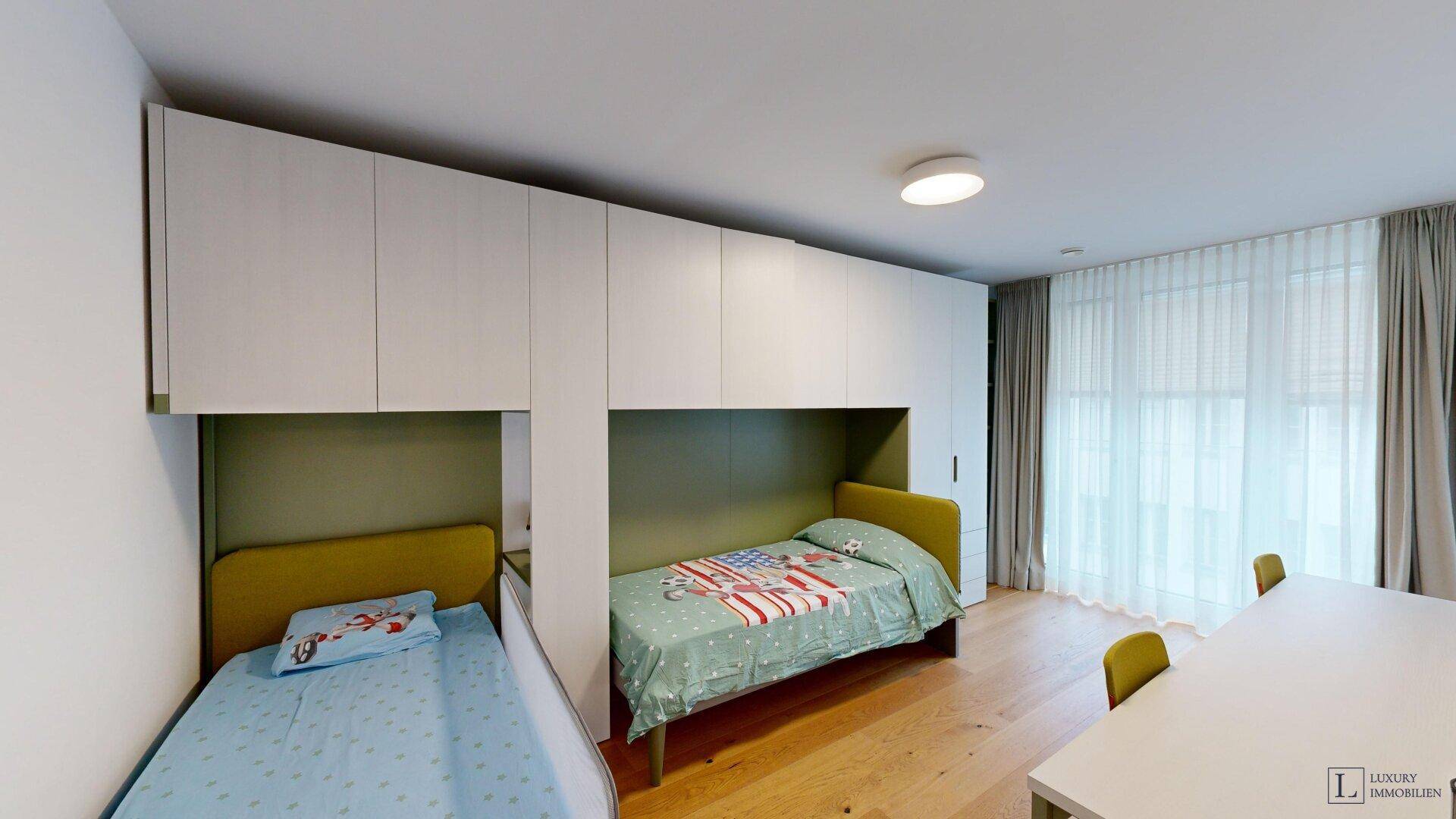 Kinderzimmer mit zwei Betten, integrierten Schränken und Holzboden.