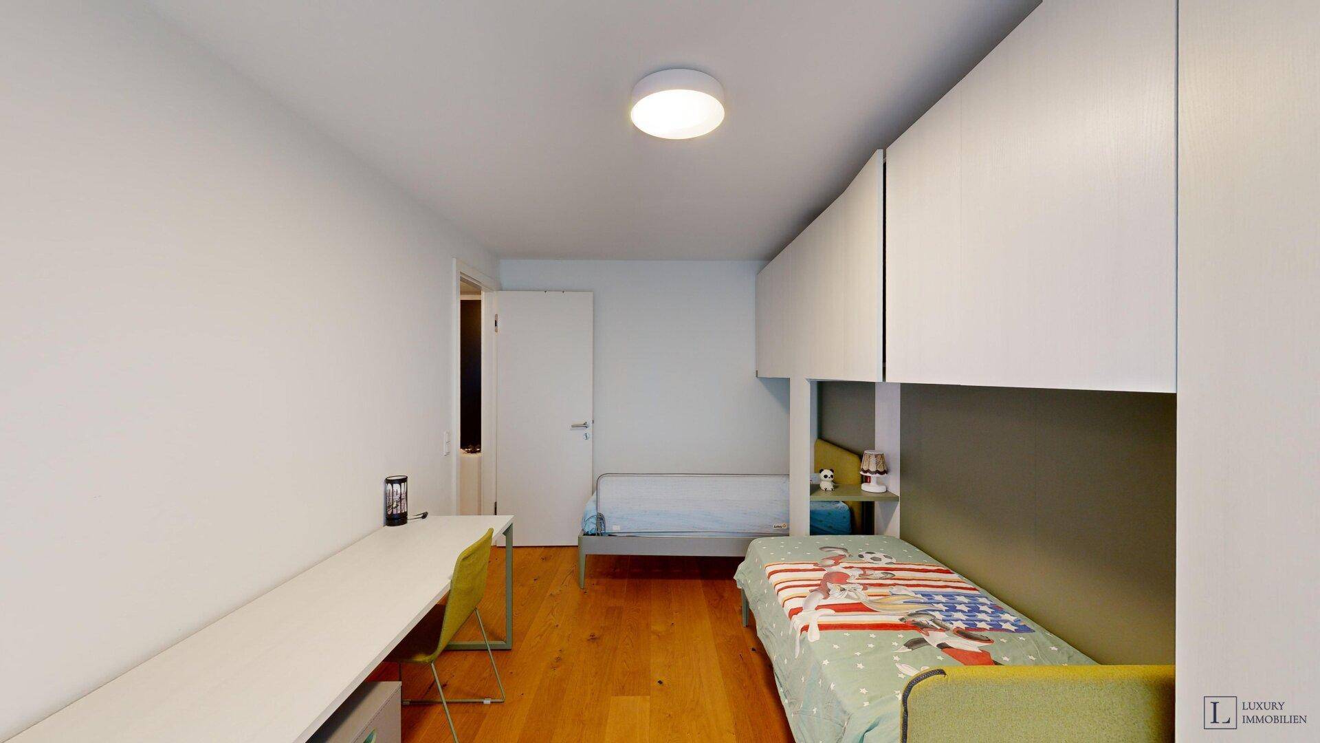 Kinderzimmer mit Schreibtisch, integrierten Betten und Stauraum.