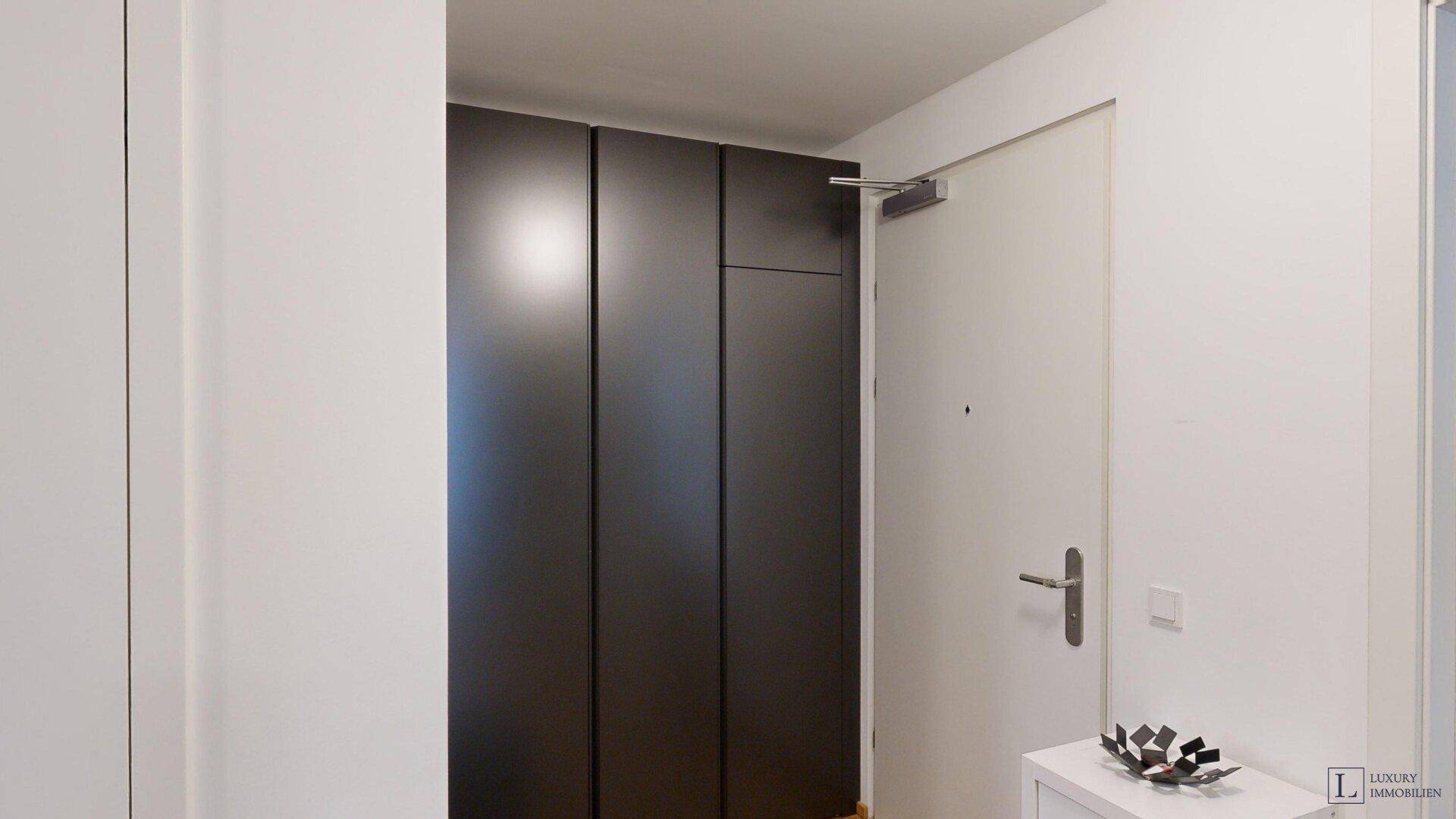 Eingangsbereich mit integrierten dunklen Schränken und heller Tür.