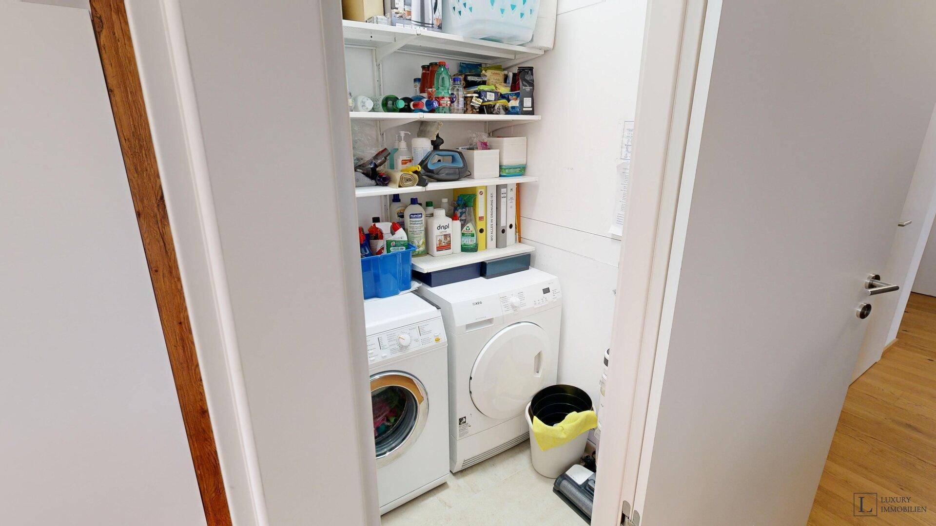 Praktischer Hauswirtschaftsraum mit Waschmaschine, Trockner und Regalen für Stauraum.