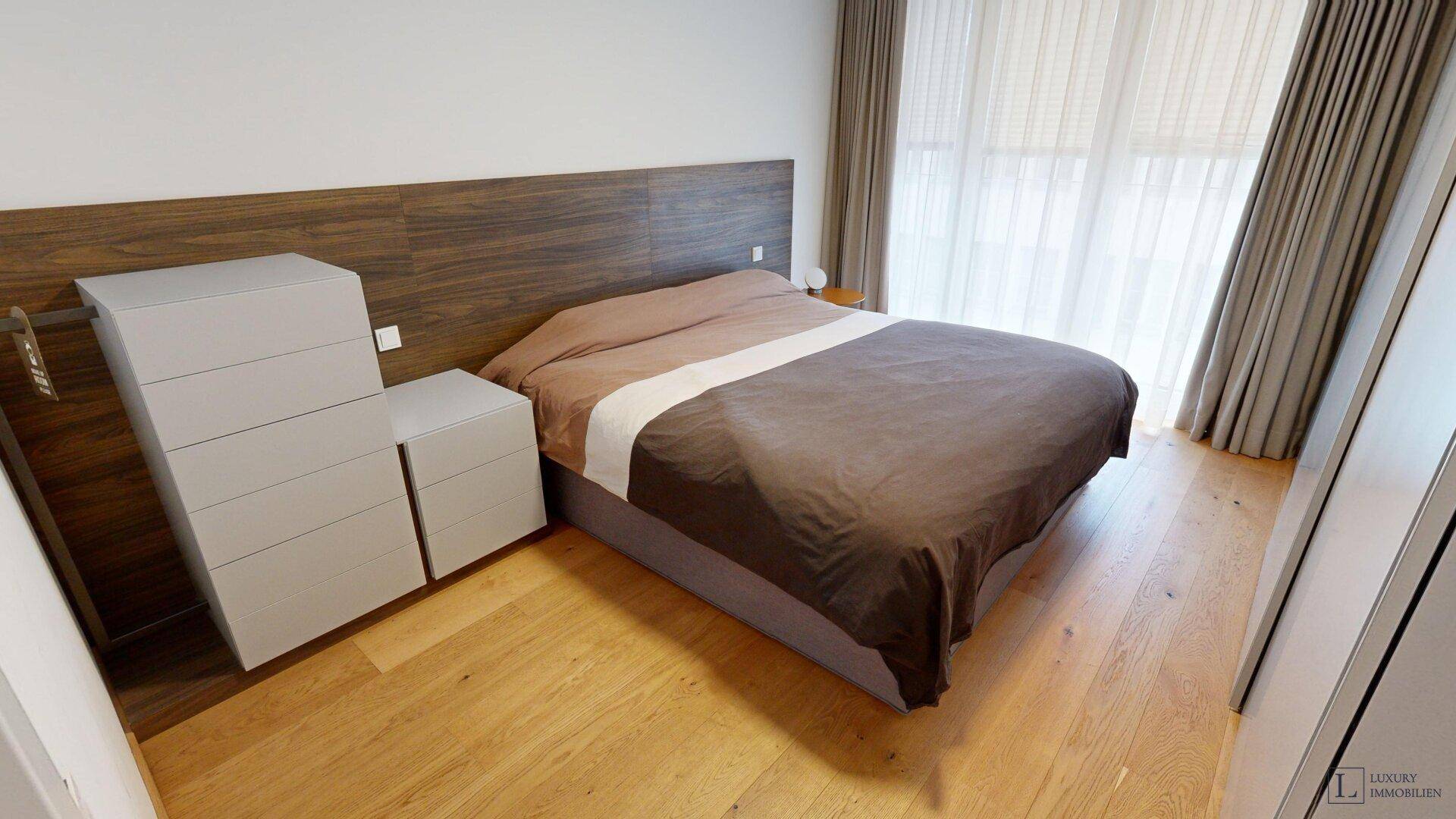 Helles Schlafzimmer mit Holzboden, großem Bett und integriertem Kopfteil.