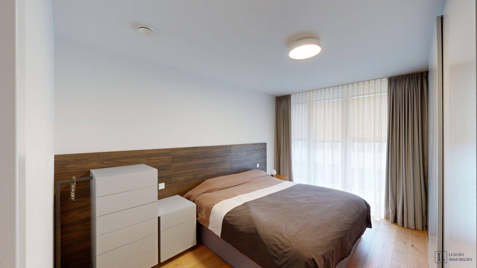 Gemütliches Schlafzimmer mit Holzboden, großem Bett und integriertem Kopfteil.