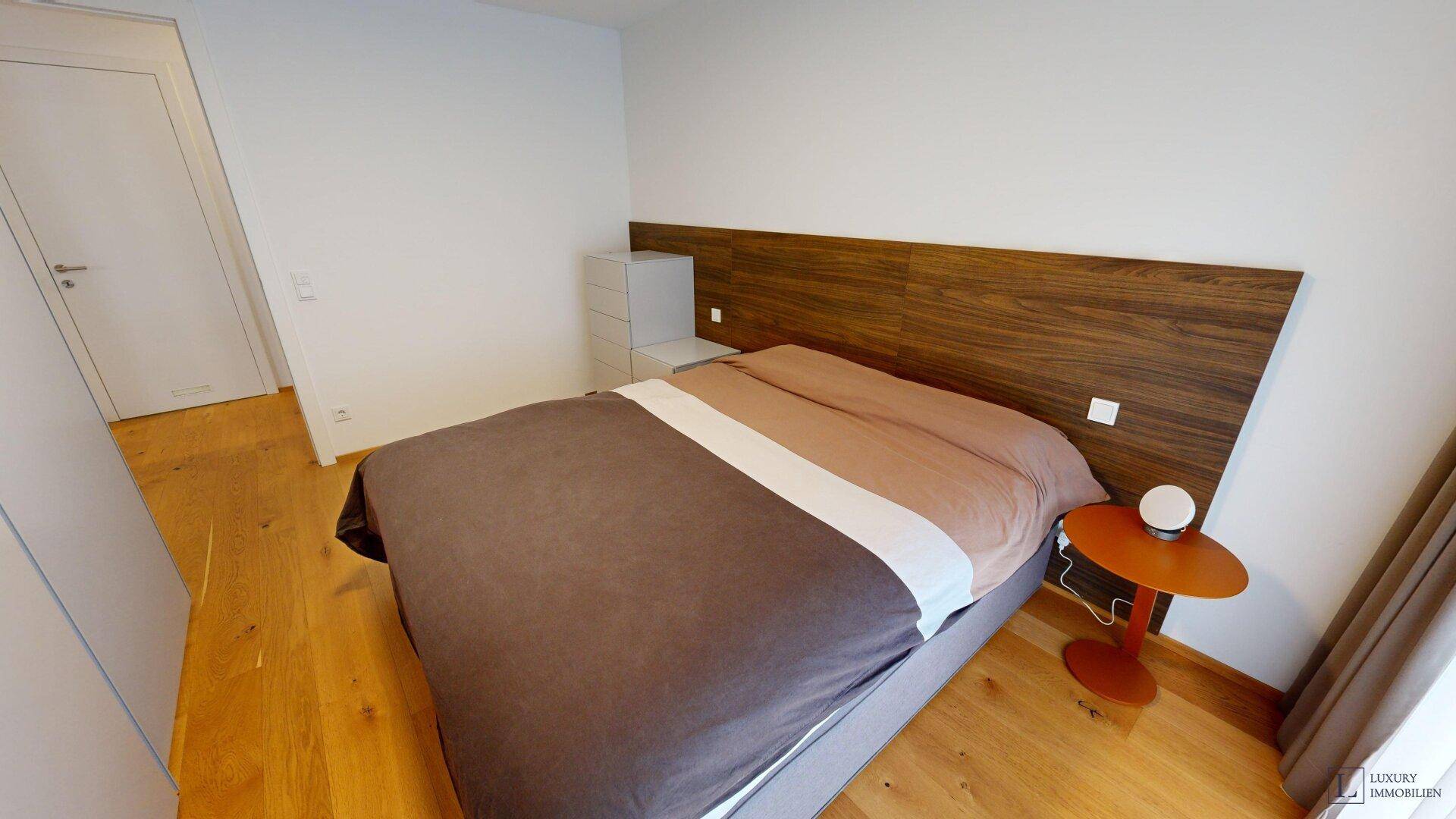 Gemütliches Schlafzimmer mit Holzboden, großem Bett und Nachttisch.