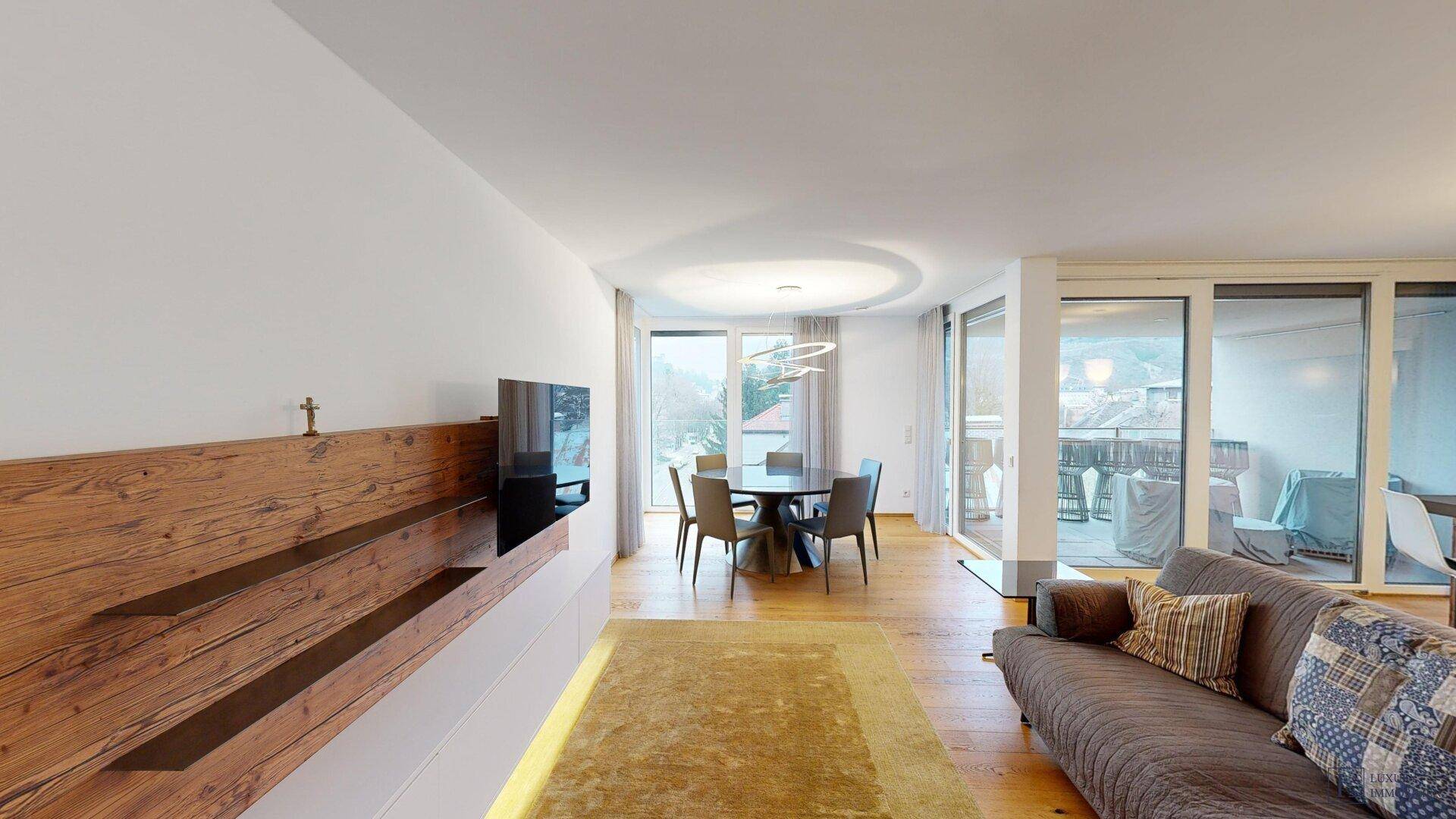 Helles, offenes Wohn-Esszimmer mit Holzboden, moderner Einrichtung und Zugang zum Balkon.