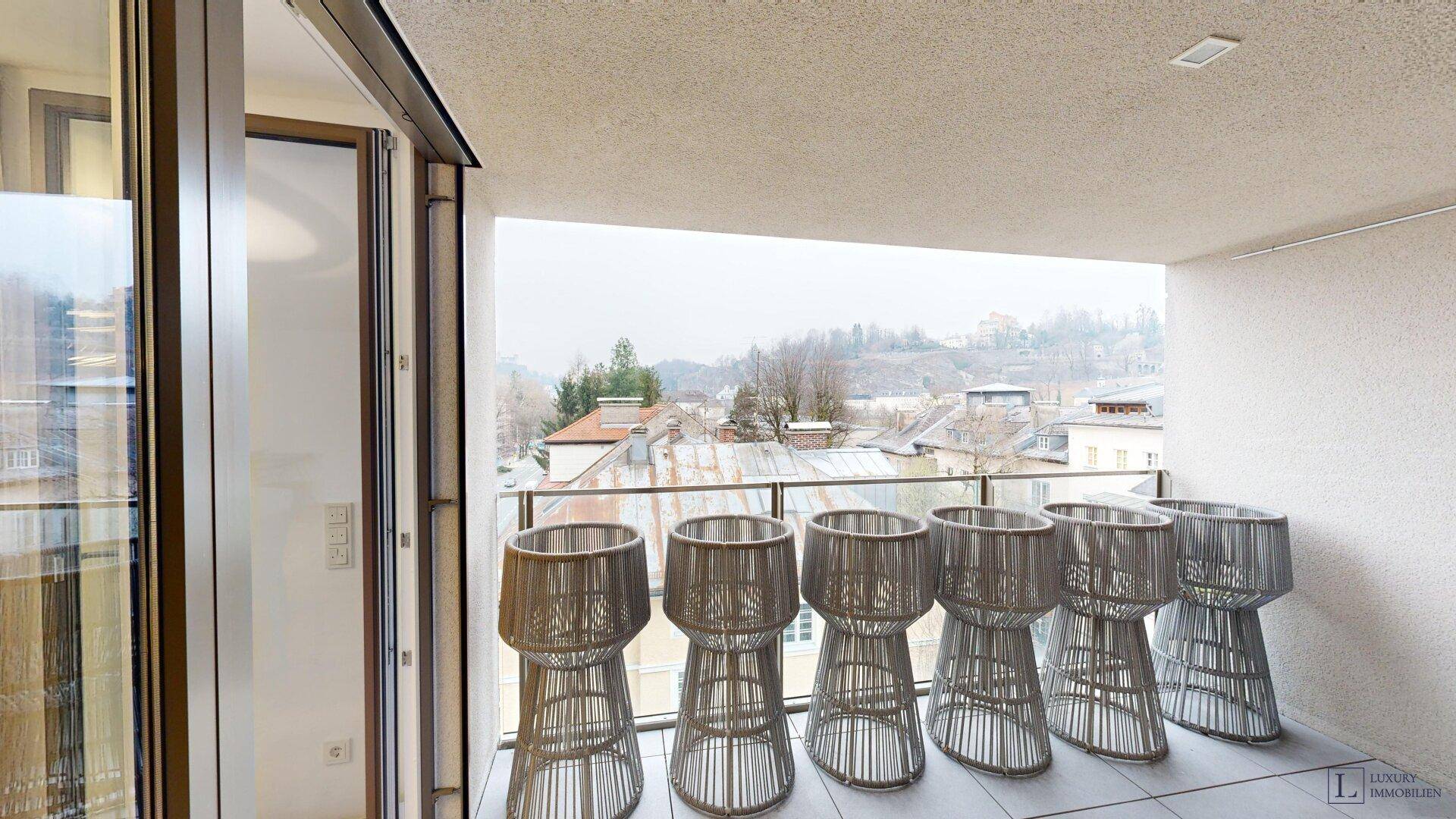 Balkon mit modernen Sitzmöbeln und weitem Blick über die Stadt.