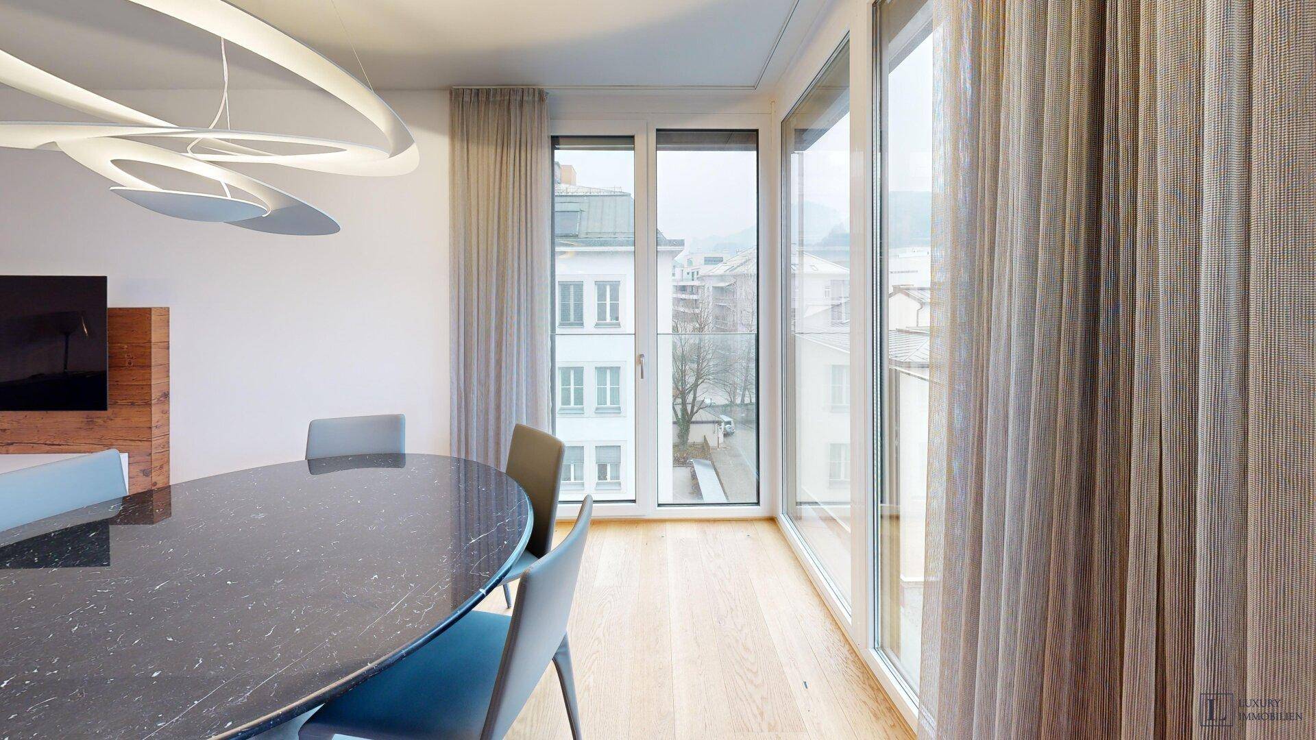 Heller Essbereich mit modernem runden Tisch, großen Fenstern und Stadtblick.