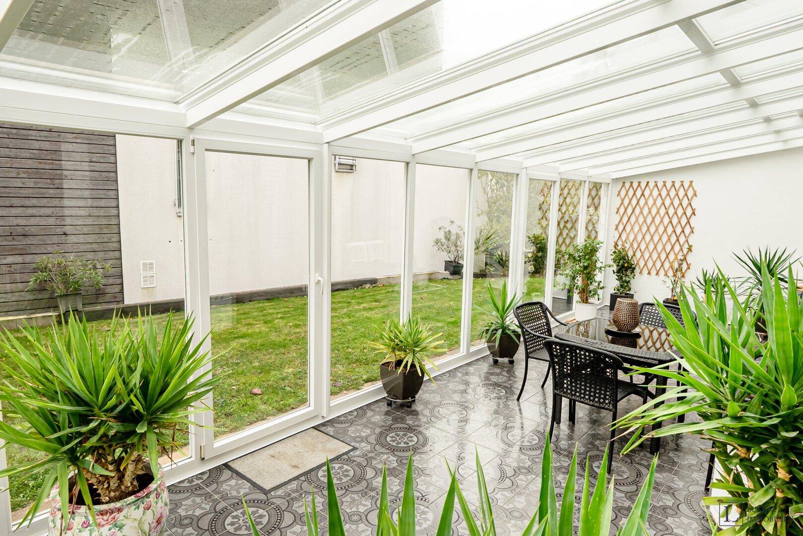 Heller Wintergarten mit Zugang zum Garten und großen Glasfronten, die viel Licht hereinlassen.