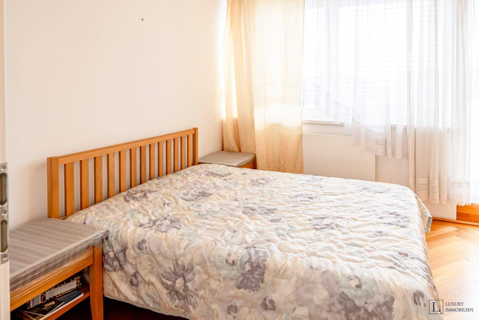 Gemütliches Schlafzimmer mit Holzbett, Nachttischen und hellem Parkettboden.