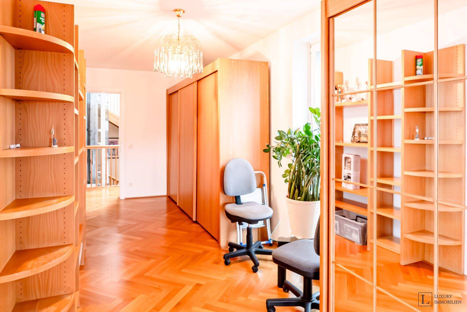 Heller Flur mit Holzregalen, Schiebetürenschrank und einem kleinen Arbeitsbereich.