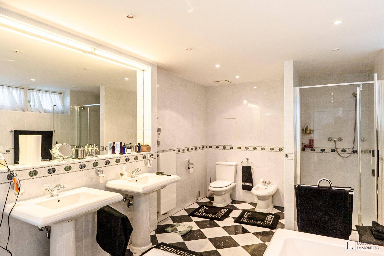 Geräumiges Badezimmer mit Doppelwaschbecken, Badewanne, Dusche und Schachbrettmuster-Fliesen.